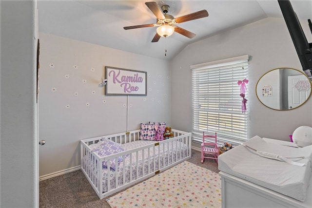 carpeted bedroom with ceiling fan, a crib, and lofted ceiling