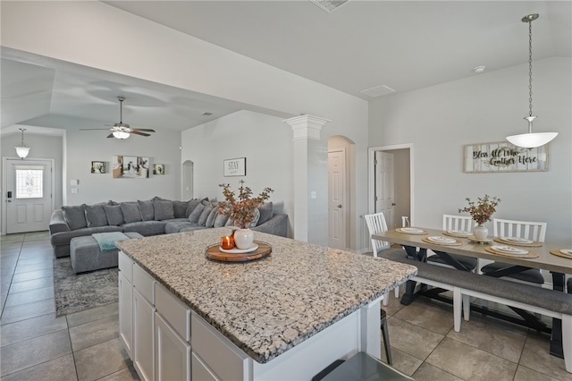 kitchen featuring white cabinetry, a kitchen island, hanging light fixtures, and vaulted ceiling