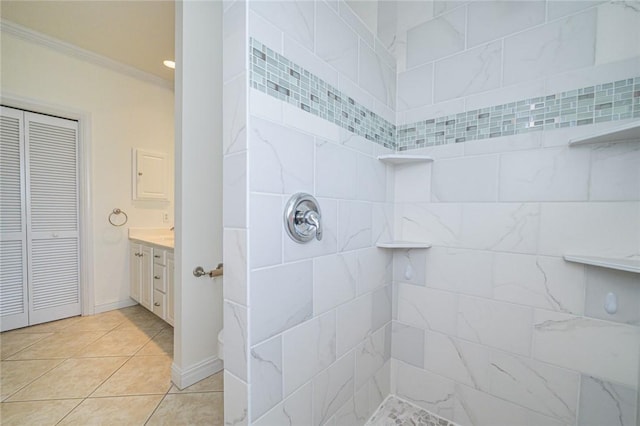 bathroom with crown molding, tile patterned flooring, vanity, tiled shower, and a closet