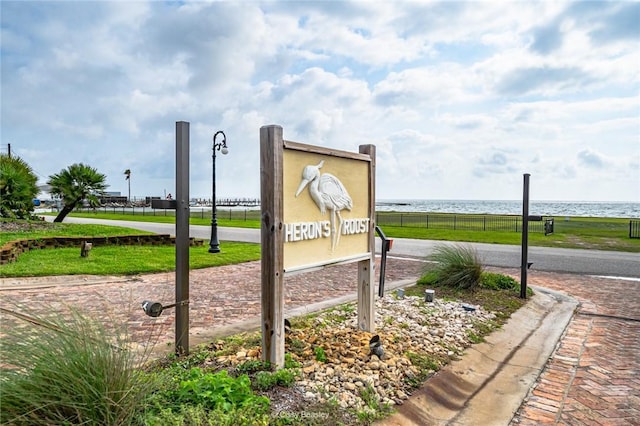 community sign featuring a water view and fence