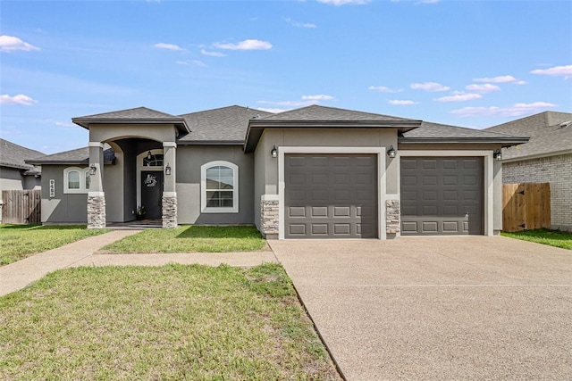 prairie-style house with an attached garage, a front lawn, fence, and concrete driveway