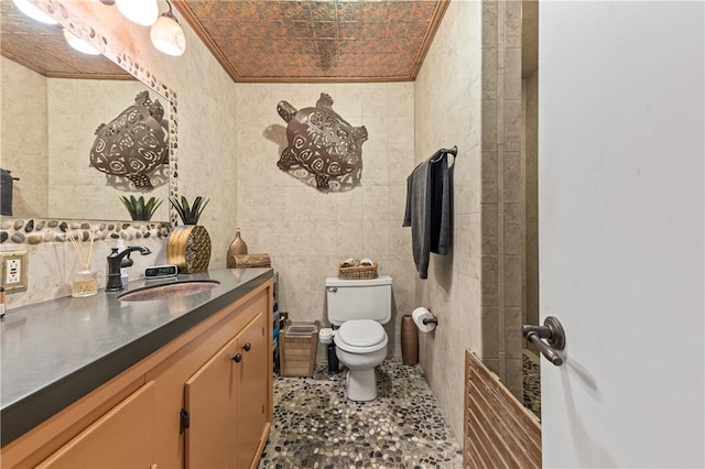 bathroom with tile walls, ornamental molding, toilet, and vanity