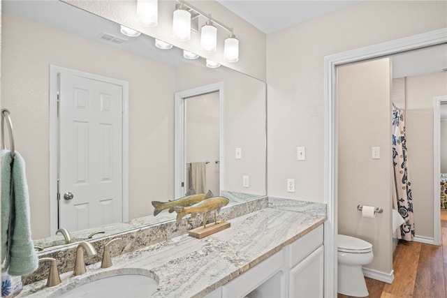 bathroom with hardwood / wood-style floors, vanity, and toilet