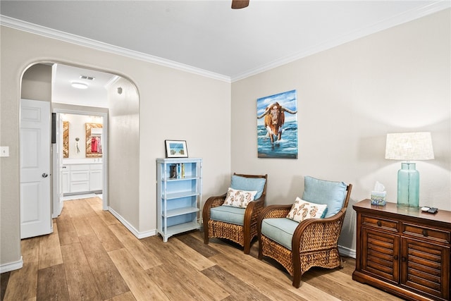 sitting room with ornamental molding and light hardwood / wood-style flooring