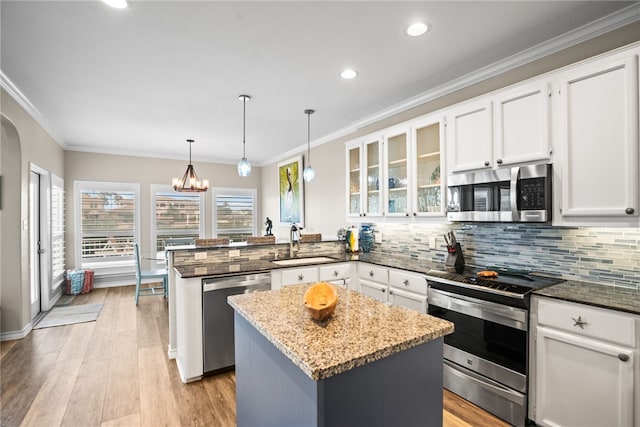 kitchen with stainless steel appliances, a kitchen island, white cabinetry, dark stone countertops, and kitchen peninsula