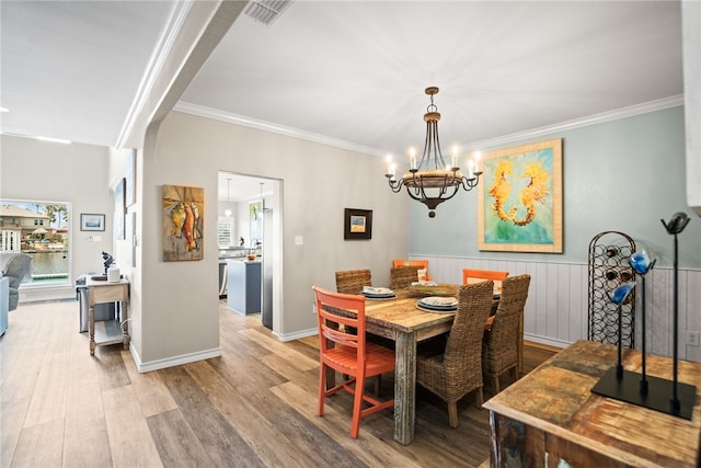 dining area featuring hardwood / wood-style floors, an inviting chandelier, and ornamental molding