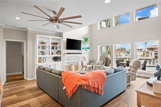 living room with hardwood / wood-style floors, ceiling fan, and crown molding