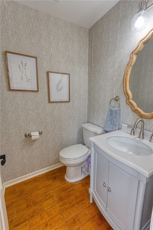 7710 Cisco, Corpus Christi, TX 78413 - half bathroom featuring wood finished floors, vanity, and wallpapered walls