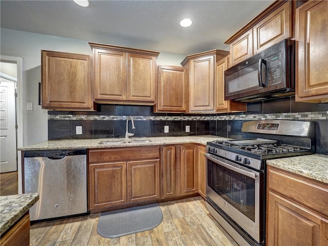 1809 Merriman Ave, Corpus Christi, TX 78412 - kitchen with light wood finished floors, light stone counters, a sink, and appliances with stainless steel finishes