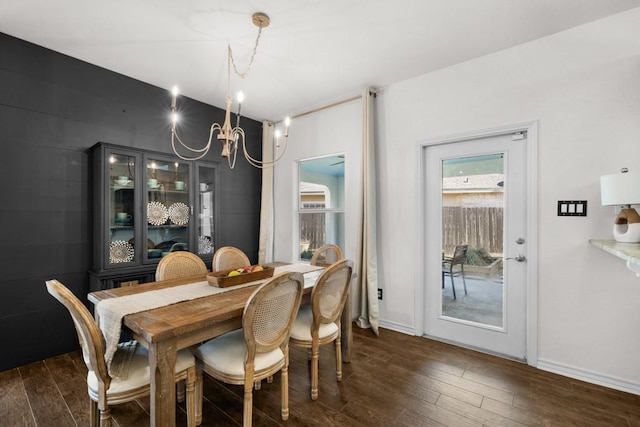 dining area with baseboards, dark wood-type flooring, and an inviting chandelier