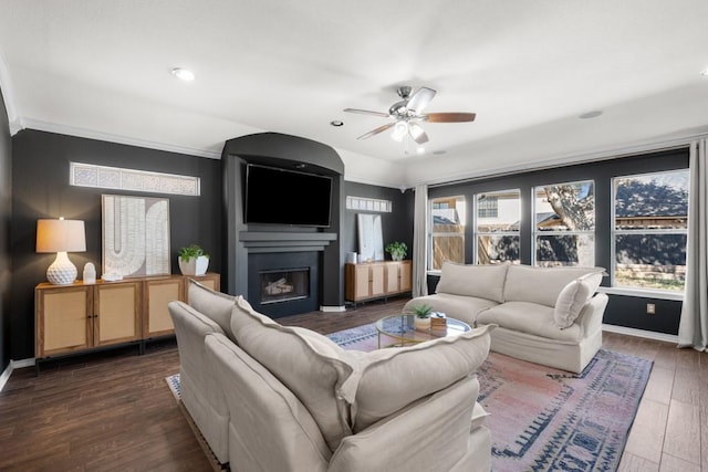 living area featuring ceiling fan, dark wood-style flooring, a fireplace, and baseboards