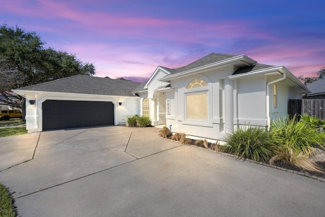 view of front facade featuring concrete driveway, an attached garage, and stucco siding