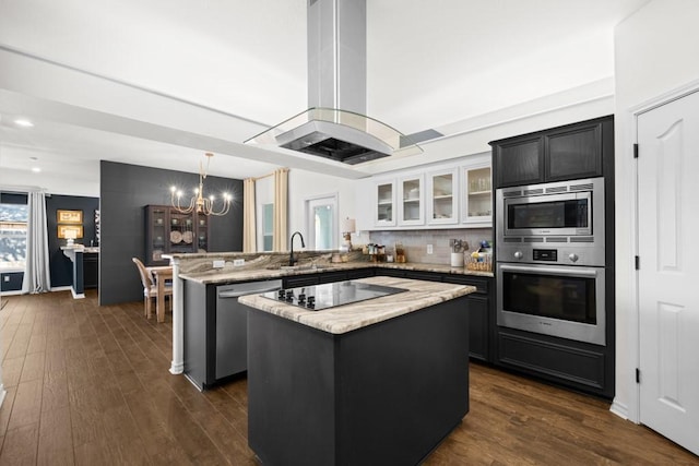 kitchen with stainless steel appliances, a peninsula, a kitchen island, white cabinetry, and glass insert cabinets