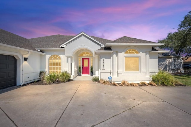 ranch-style house featuring a garage, driveway, a shingled roof, and stucco siding