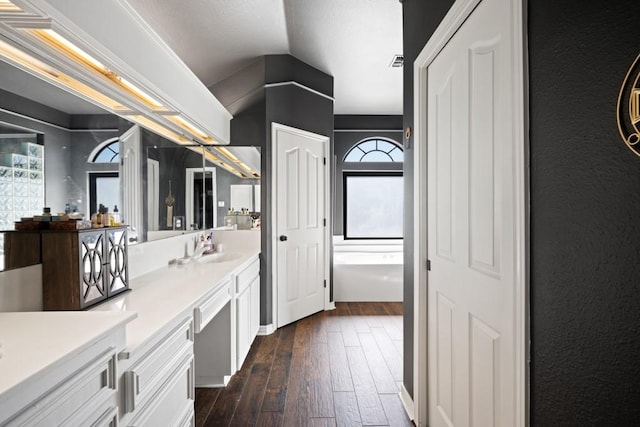 bathroom featuring wood-type flooring, visible vents, vaulted ceiling, and vanity