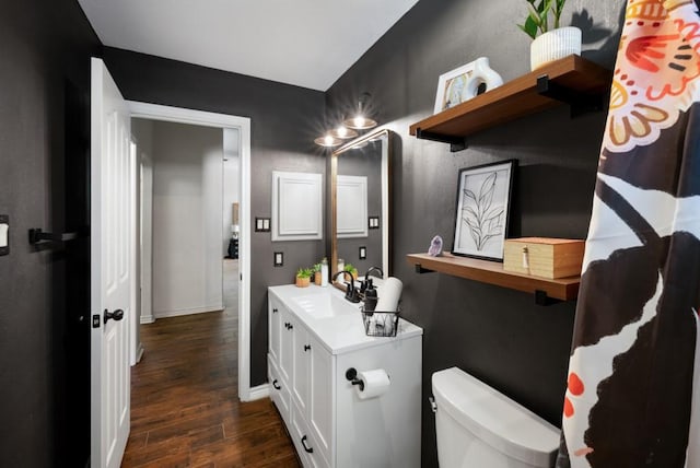 bathroom featuring toilet, wood finished floors, vanity, and baseboards