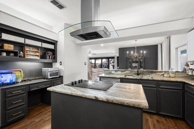 kitchen with light stone counters, dark cabinets, a center island, black electric stovetop, and a sink