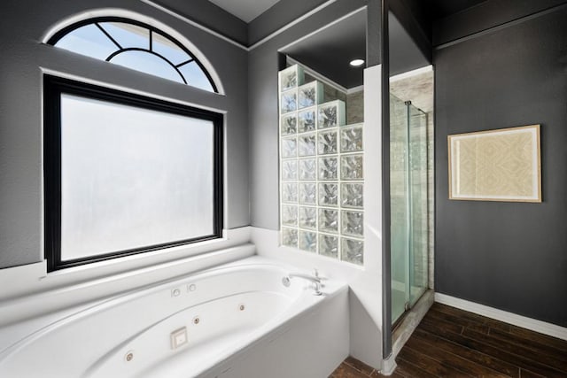 bathroom featuring a whirlpool tub, a stall shower, wood finished floors, and baseboards