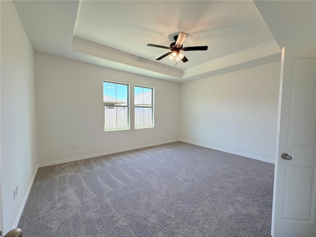 empty room with a raised ceiling, crown molding, carpet, and ceiling fan