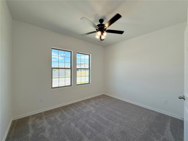 spare room with ceiling fan and dark carpet