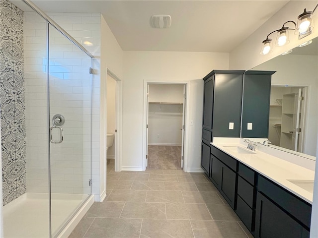 bathroom featuring tile patterned floors, vanity, a shower with shower door, and toilet