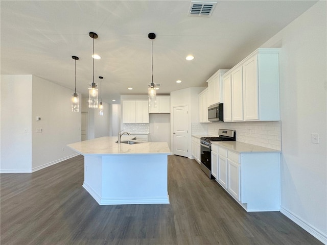 kitchen with a kitchen island with sink, white cabinetry, pendant lighting, and stainless steel appliances