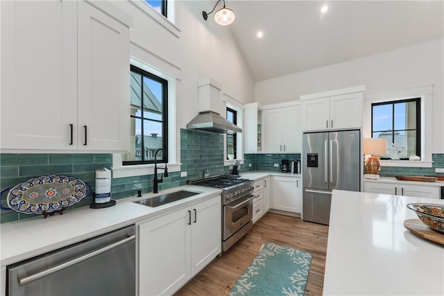 kitchen with stainless steel appliances, wall chimney exhaust hood, a healthy amount of sunlight, and sink