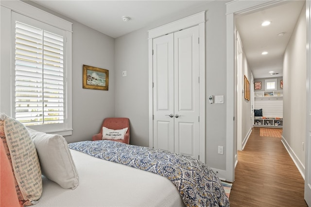 bedroom with a closet, recessed lighting, baseboards, and wood finished floors