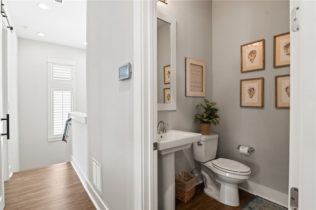 half bath featuring visible vents, baseboards, toilet, and wood finished floors