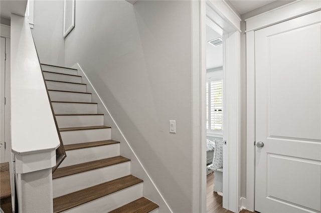 staircase with visible vents and wood finished floors