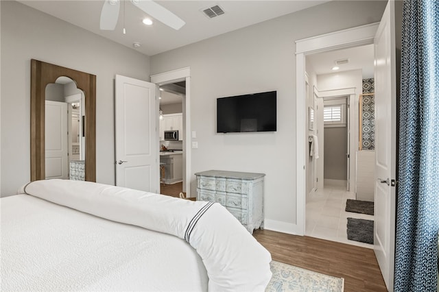 bedroom featuring visible vents, wood finished floors, recessed lighting, arched walkways, and baseboards