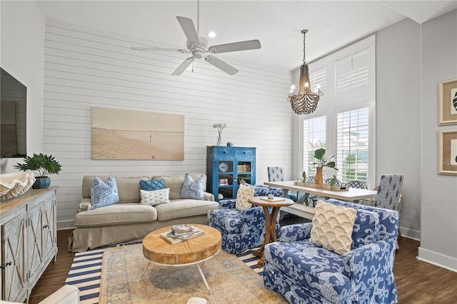 living area featuring baseboards, dark wood finished floors, and ceiling fan with notable chandelier