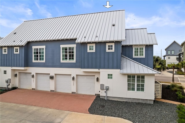 back of property with board and batten siding, metal roof, decorative driveway, and a standing seam roof