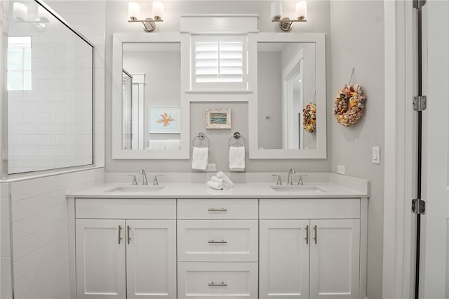 bathroom with double vanity, walk in shower, and a sink