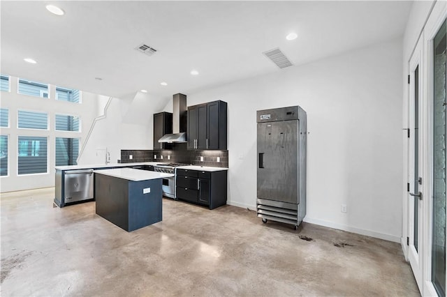 kitchen with decorative backsplash, appliances with stainless steel finishes, a center island, and wall chimney exhaust hood