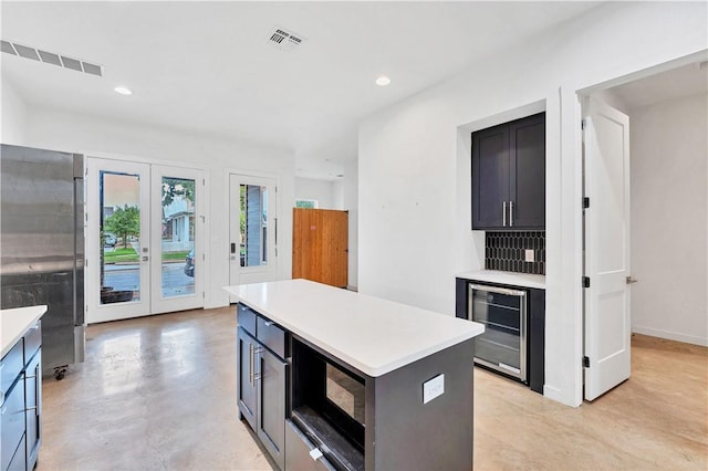 kitchen featuring decorative backsplash, french doors, beverage cooler, a kitchen island, and stainless steel refrigerator