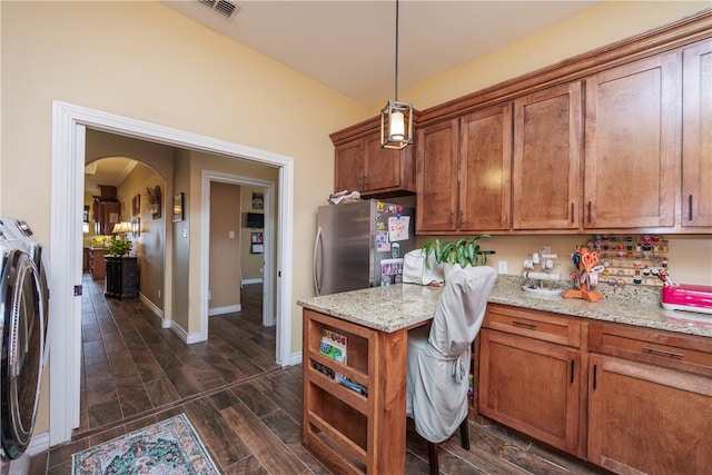 kitchen with stainless steel refrigerator, light stone counters, dark hardwood / wood-style flooring, pendant lighting, and washer and dryer