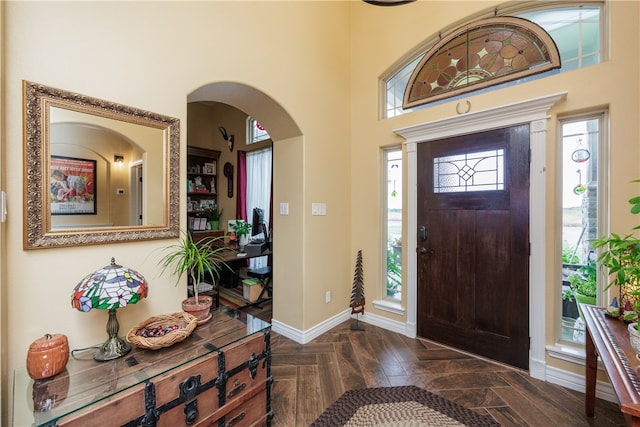 foyer entrance featuring dark parquet flooring and a high ceiling