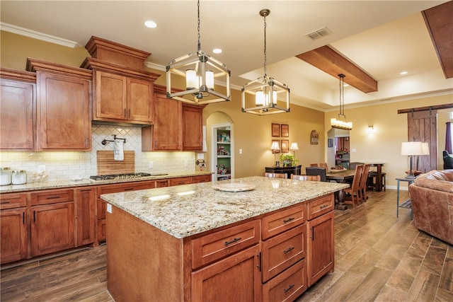 kitchen with dark wood-type flooring, crown molding, a barn door, a kitchen island, and hanging light fixtures