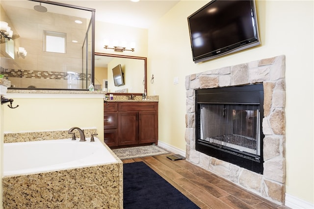 bathroom with hardwood / wood-style floors, vanity, a fireplace, and independent shower and bath