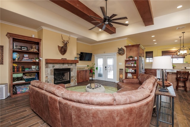 living room with french doors, dark hardwood / wood-style flooring, ceiling fan, beam ceiling, and a stone fireplace