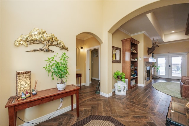 entryway with dark parquet floors, ornamental molding, a high ceiling, and french doors