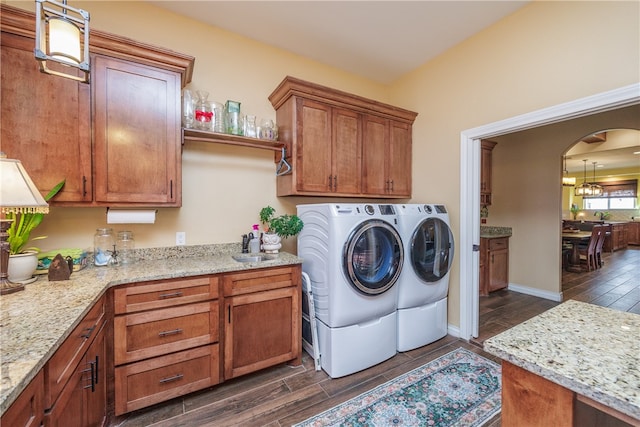 laundry area with cabinets, washing machine and dryer, a chandelier, and dark wood-type flooring