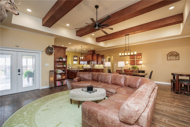 living room with dark wood-type flooring, french doors, ceiling fan with notable chandelier, ornamental molding, and beam ceiling