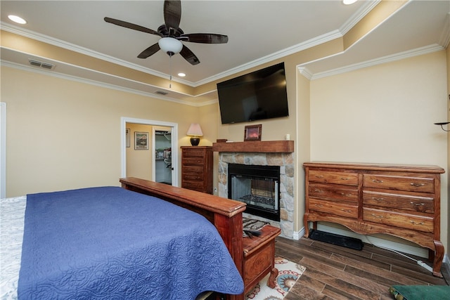 bedroom featuring ceiling fan, a fireplace, dark hardwood / wood-style floors, and ornamental molding