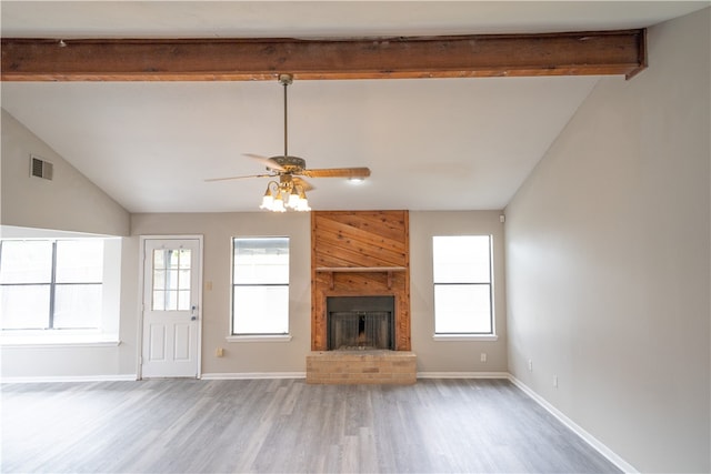 unfurnished living room with hardwood / wood-style flooring, plenty of natural light, and vaulted ceiling with beams