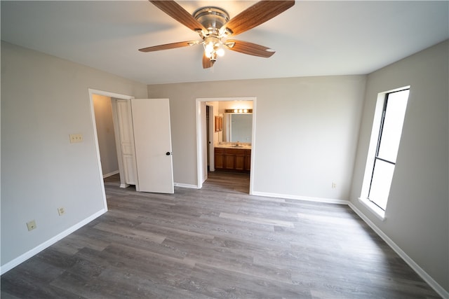 unfurnished bedroom featuring dark wood-type flooring, ensuite bathroom, and ceiling fan