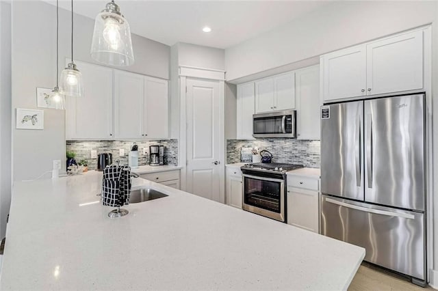 kitchen with hanging light fixtures, backsplash, stainless steel appliances, and white cabinets