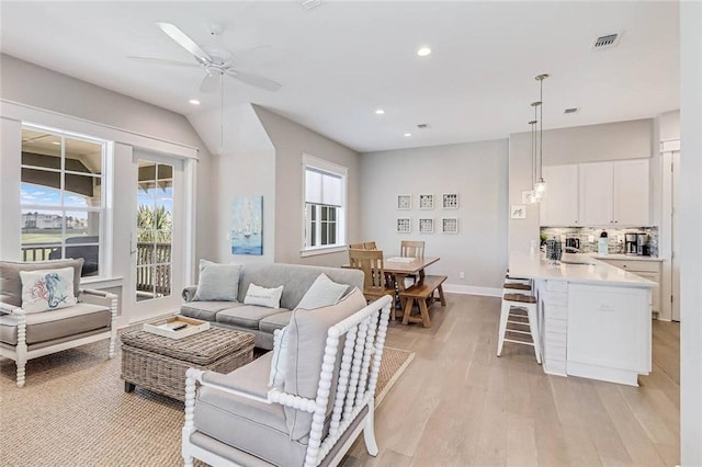 living room with ceiling fan, a wealth of natural light, and light wood-type flooring