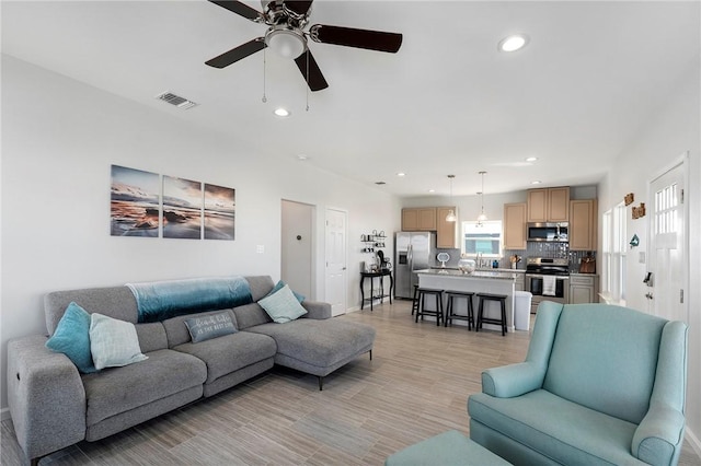 living room with a wealth of natural light, visible vents, and recessed lighting